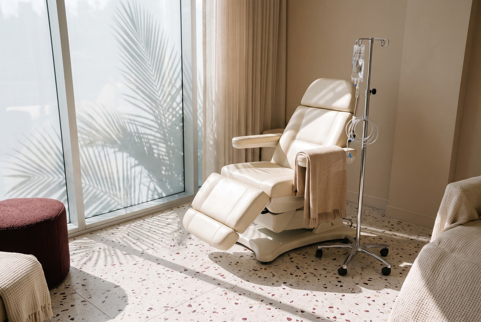 An empty reclining treatment chair beside a chrome IV pole and drip bag in a bright Los Angeles infusion suite